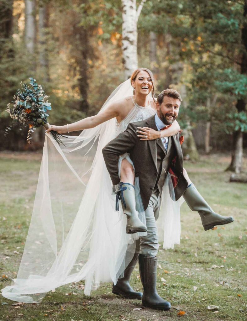 Bride and groom in wellies and piggybacking at their celebrant-led wedding