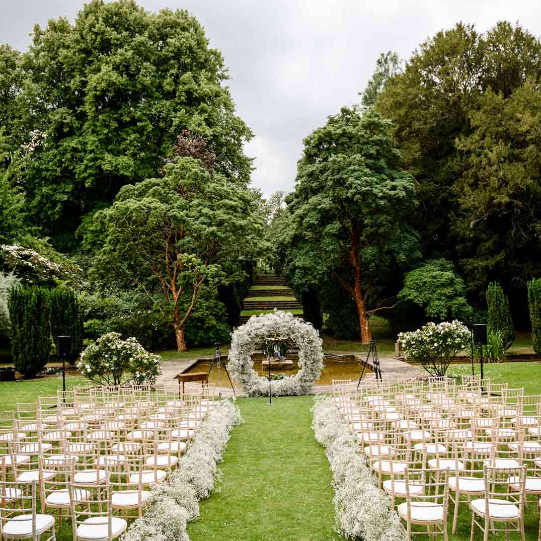 Chairs and a flower arch in gardens, the perfect setting for an outdoor celebrant-led wedding